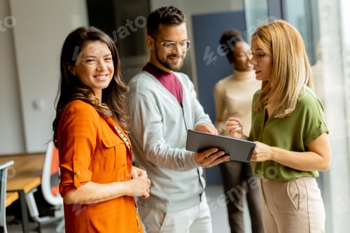 Preview: Young business woman standing in front of her team at the office