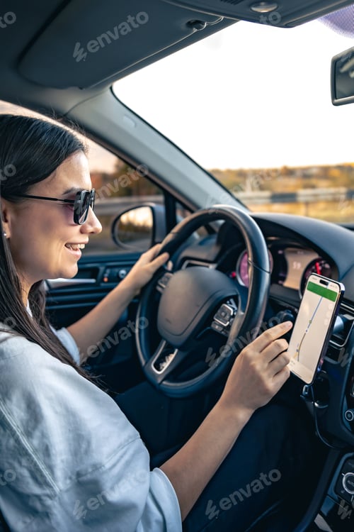Preview: An attractive young woman driving a car uses a navigator.