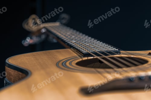 Preview: Close-up of an acoustic guitar on a dark background.