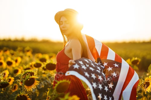 Preview: Beautiful girl in hat with the American flag in a sunflower field. 4th of July. Fourth of July.