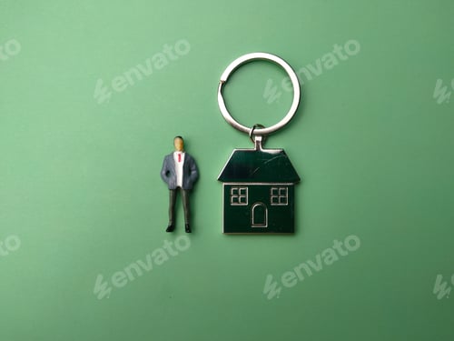 Preview: Miniature people and house keychain on a green background. The concept of get new home.