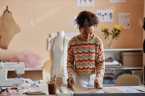 Preview: Young creative craftswoman bending over table with sewing patterns