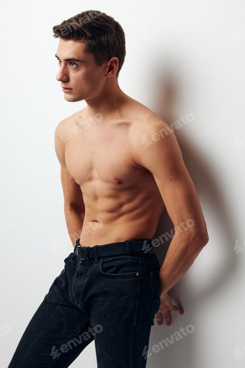 Preview: Side view of a man in trousers with a bare torso leaning against the wall