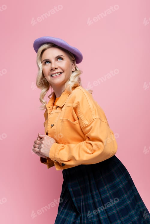 Preview: Pretty blonde woman in jacket looking up isolated on pink