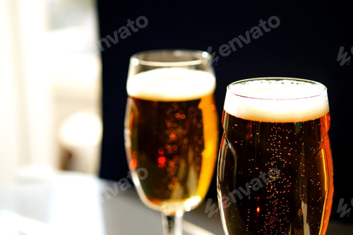 Vista previa: Two glasses of light lager beer on the table.
