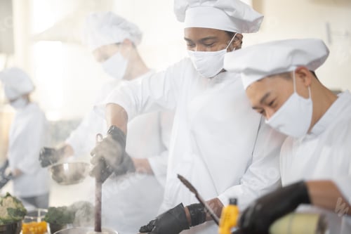 Preview: Multiracial team of chef cooks cooking together in the kitchen