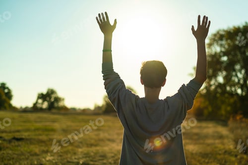 Preview: young happy guy enjoy life with raised hands against the sky looking at the sunset а