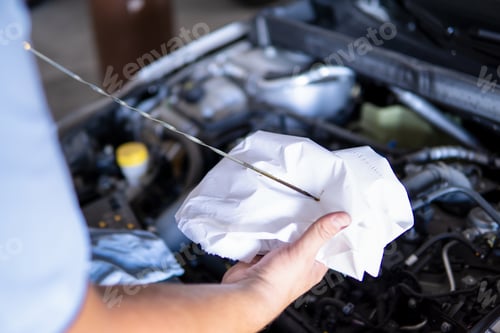 Preview: Auto mechanic checking the engine oil level of a car in a garage