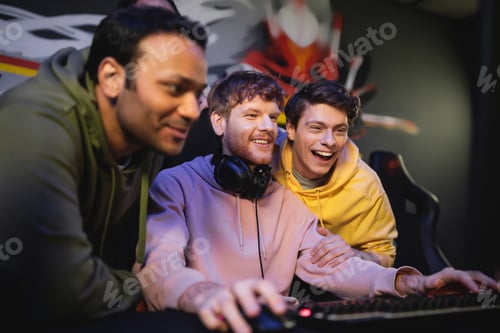 Preview: Smiling man playing video game near multiethnic friends in gaming club