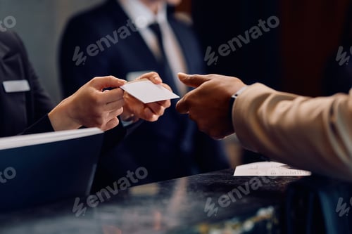 Preview: Close up of black man receiving room cardkey while checking in at the hotel.