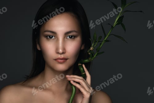 Preview: Beautiful asian woman with a bamboo plant in her hands