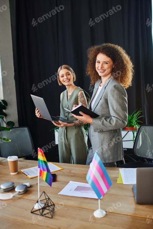 Preview: Coworkers proudly embracing diversity in a vibrant office setting with Pride flags