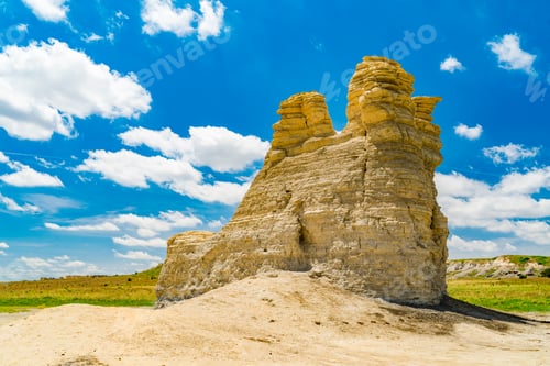 Preview: three stone formations on the field of grass and dirt under a blue sky with white