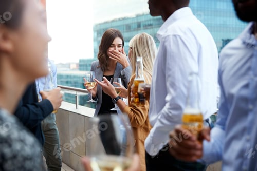 Preview: Office colleagues socialising with drinks on a balcony in the city after work