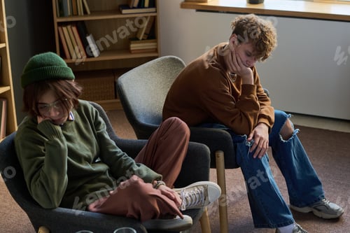 Preview: Two Teenagers Sitting in Group Therapy Session Appearing Thoughtful