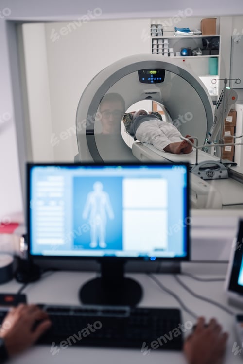 Preview: Technician conducting a CT scan while monitoring from screen.