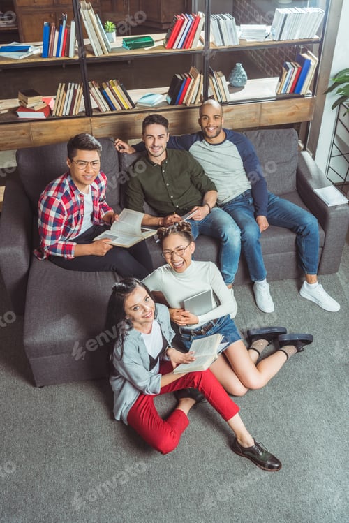 Preview: high angle view of happy multiethnic students studying together and smiling at camera