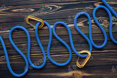Preview: Long blue knot. Isolated photo of climbing equipment. Parts of carabiners lying on the wooden table
