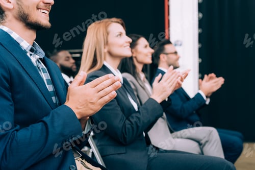 Preview: smiling multicultural businesspeople applauding during business seminar in conference hall