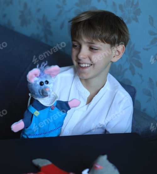 Preview: A cute blond boy of 10 years old put handmade rag dolls on his hands and smiles with an open smile
