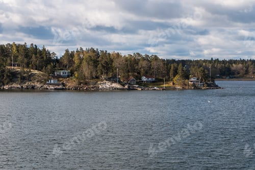 Preview: view from the ship to the rocky coast of Sweden. typical swedish houses on the rocks. cloudy sky