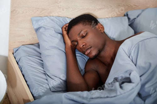 Preview: Contemplating dreams: man in bed with hand on head