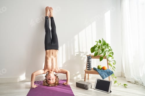 Preview: Shirtless child closing eyes in headstand in light room