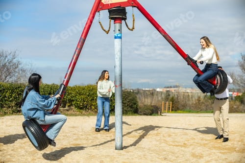Preview: Friends spinning on playground merry go round, enjoying sunny day outdoors