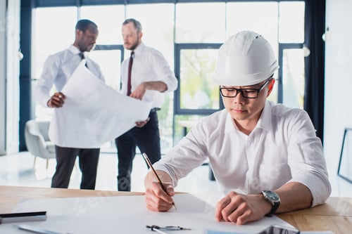 Preview: architect working on new project with colleagues behind in modern office