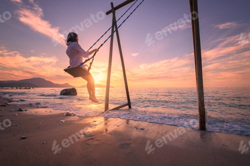 Preview: Happy young woman on wooden swing in water, sea with waves