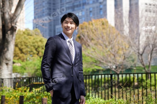 Preview: A Japanese male businessman standing in the background of a building.