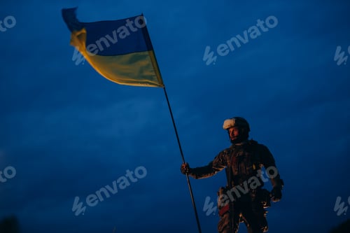Preview: Portrait of male Ukrainian warrior holding a national flag in the evening