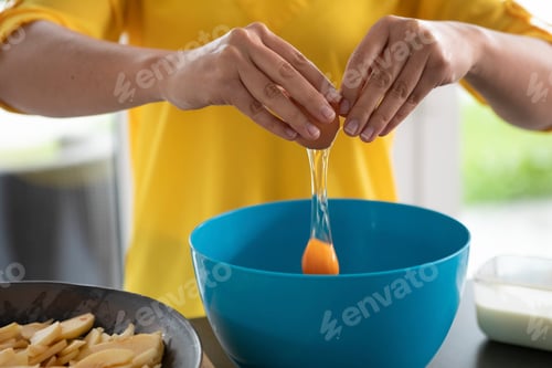 Preview: Hands cracking an egg into a blue bowl for cooking