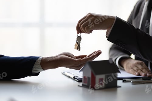 Preview: Real estate agent holding house keys is handing them over to a client.