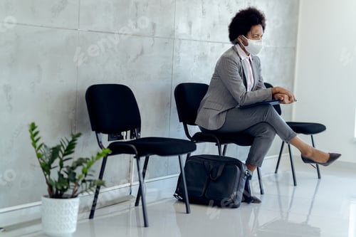 Preview: Black pensive businesswoman with face mask waiting for job interview.