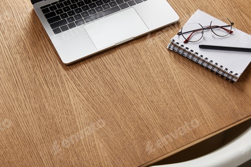 Aperçu: high angle view of laptop, notebook, glasses and pen on wooden tabletop