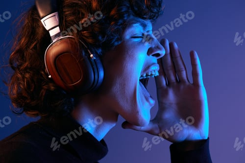 Preview: Male singer wearing headphones listening to music and singing with his mouth open, sound recording