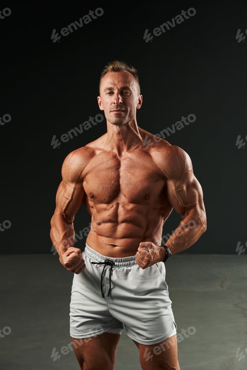 Preview: caucasian man with a naked torso in shorts clenches his fists, strains the muscles of the press