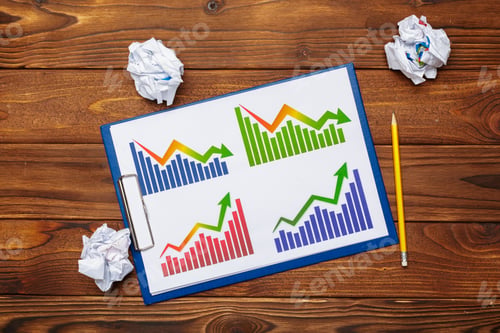 Preview: Charts showing varying sales trends on a clipboard with crumpled paper on a wooden table