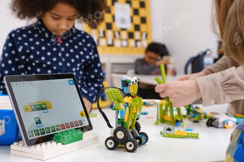 Preview: Multi ethnic children at technology lesson coding robot on tablet