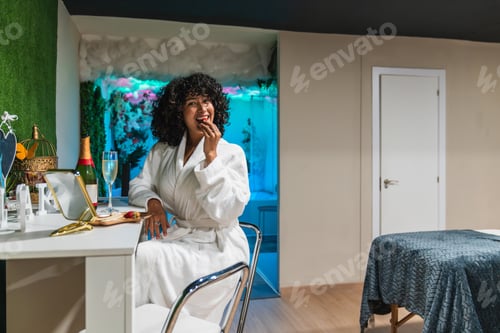 Preview: Beautician enjoying strawberries and champagne during break at beauty spa
