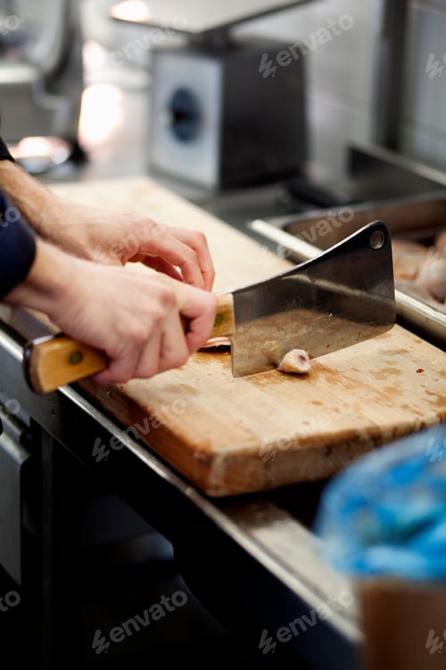 Preview: Cropped image of chef chopping meat on cutting board in restaurant kitchen