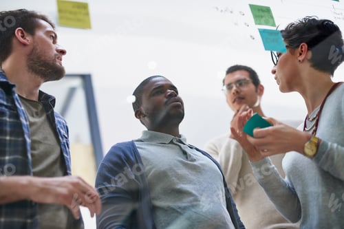 Preview: Shot of a group of designers brainstorming with notes on a glass wall in an office