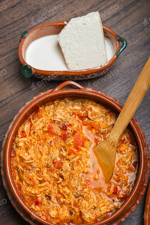 Preview: Authentic mexican chicken tinga, typical mexican food prepared in a clay pot on a wooden table.
