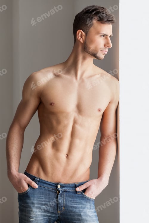 Preview: Thoughtful handsome man. Thoughtful young muscular man looking away while standing near the window