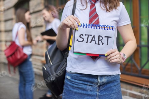 Preview: Start. Girl student holds notebook with word start