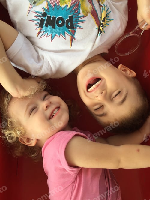 Laughing Children Lying on a Red Surface