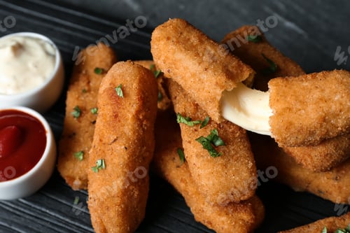 Preview: Pile of tasty cheese sticks and sauces on table, closeup