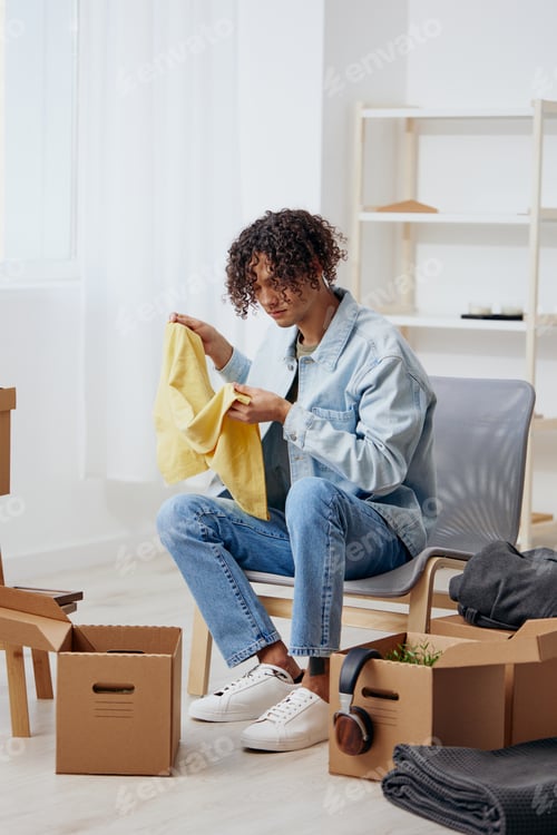 Preview: guy with curly hair cardboard boxes in the room unpacking interior
