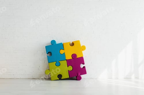 Preview: colorful connected jigsaw pieces near white brick wall at home